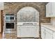 Close up of the kitchen cooktop, oven and cabinets with unique brick surround and design at 1810 Tamerlane Pl, Brandon, FL 33510