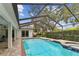 Pool and hot tub in screened-in enclosure, patio with brick flooring, landscaping, and blue skies at 1810 Tamerlane Pl, Brandon, FL 33510