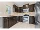 Modern kitchen with stainless steel appliances, dark cabinets, and tile flooring at 2020 Greenwood Valley Dr, Plant City, FL 33563