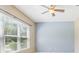 This bedroom features a ceiling fan, a large window with blinds, and a blue accent wall at 25950 Risen Star Dr, Wesley Chapel, FL 33544