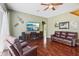 Inviting living room featuring hardwood floors, a ceiling fan, and a media center with a fireplace at 25950 Risen Star Dr, Wesley Chapel, FL 33544