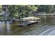 Picturesque boat dock and lift on the water, surrounded by lush greenery and moss-draped trees at 2850 Doone Cir, Palm Harbor, FL 34684