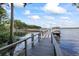 Scenic view of the boat dock, with railing, leading to the serene lake and a covered boat at 2850 Doone Cir, Palm Harbor, FL 34684