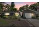 Charming single-story home with lush landscaping, a garage, and a welcoming entrance at dusk at 2850 Doone Cir, Palm Harbor, FL 34684