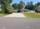 Landscaped front yard featuring a well-maintained lawn, driveway with truck and boat, and mature trees on a sunny day at 310 4Th Ave. Southwest, Ruskin, FL 33570