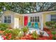 Charming home featuring a vibrant red door, colorful chairs, and lush landscaping for a welcoming entrance at 3129 W Villa Rosa St, Tampa, FL 33611