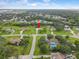 Birds eye view of a neighborhood with tree lined streets, green lawns, and houses under a bright blue sky at 3515 E 34Th St, Bradenton, FL 34208