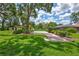 Expansive backyard with lush landscaping, a green sport court, and a screened pool in the distance at 3923 Hudson Ln, Tampa, FL 33618