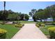 A well-maintained park with a brick walkway, manicured landscaping, benches, mature trees, and a distant view of the water at 4147 Grandchamp Cir, Palm Harbor, FL 34685