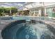 Tranquil spa and pool area with stone accents and a screened enclosure for year-round enjoyment at 4147 Grandchamp Cir, Palm Harbor, FL 34685