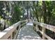 A wooden boardwalk winding through a lush, green area with moss-covered trees creating a serene and natural setting at 4147 Grandchamp Cir, Palm Harbor, FL 34685
