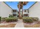 Condominium exterior showcasing stucco walls, screened balconies, green shrubs, and a walkway on a sunny day at 4611 W North B St # 228, Tampa, FL 33609