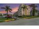 Exterior view of building with parking lot, tropical palms, and colorful sunset sky at 5623 80Th N St # 415, St Petersburg, FL 33709
