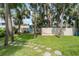 A fun, grassy backyard area with an activity center, mature trees, and a privacy fence at 58 Aster St, Clearwater Beach, FL 33767