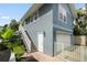 Two-story home with stairs leading to the entry, white picket fence, white garage door, and manicured landscaping at 58 Aster St, Clearwater Beach, FL 33767