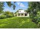 Expansive backyard featuring lush green grass, mature trees, and a covered patio of a modern home at 5816 S 3Rd St, Tampa, FL 33611