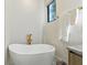 Bright bathroom featuring a sleek freestanding tub, gold fixtures, and a window for natural light at 5816 S 3Rd St, Tampa, FL 33611