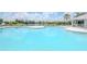 A sparkling blue community pool with plenty of lounge chairs, umbrellas, and a lush green backdrop at 6231 Olivedale Dr, Riverview, FL 33578