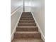 Carpeted staircase leading up to the second floor with white walls and handrail, offering a clean and bright entry at 6262 142Nd N Ave # 1302, Clearwater, FL 33760