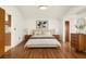 Stylishly staged bedroom with hardwood flooring, a bed, wooden bedside tables and attractive wall art at 6706 Dunes Ln, Temple Terrace, FL 33617