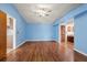Spacious, light-filled living room with beautiful hardwood flooring, a ceiling fan, and blue painted walls at 6706 Dunes Ln, Temple Terrace, FL 33617