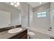Well-lit bathroom featuring granite countertop, a tub and shower combination and a decorative mirror at 7408 Sungold Meadow Ct, Apollo Beach, FL 33572