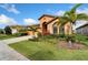 Single-story home featuring a two-car garage, arched entry, and vibrant tropical landscaping at 7408 Sungold Meadow Ct, Apollo Beach, FL 33572