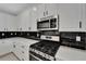 Modern kitchen featuring stainless steel appliances, white cabinetry, and contrasting black tile backsplash at 7408 Sungold Meadow Ct, Apollo Beach, FL 33572