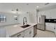 Modern kitchen featuring a stainless steel refrigerator, white cabinets, and black backsplash at 7408 Sungold Meadow Ct, Apollo Beach, FL 33572