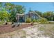 Exterior view of a charming single-story home with a landscaped yard, mature tree and a screened porch at 917 W Idlewild Ave, Tampa, FL 33604