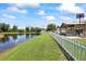 Backyard with pond view, featuring a white picket fence and covered patio with a grill at 9831 Edmonton Dr, Land O Lakes, FL 34638