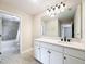 Well-lit bathroom with white vanity, granite countertops, a large mirror, and access to the bathtub/shower area at 11828 Ranchers Gap Dr, Odessa, FL 33556