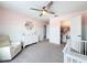 Stylish Bedroom with pink walls, white paneling, a crib, plush armchair, and a walk-in closet for ample storage at 11828 Ranchers Gap Dr, Odessa, FL 33556
