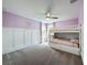 Charming bedroom with lavender walls, wainscoting, and a white bunk bed featuring floral accents and coordinating bedding at 11828 Ranchers Gap Dr, Odessa, FL 33556