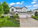 Beautiful two-story home featuring a three-car garage, lush landscaping, and a welcoming front porch with an American flag at 11828 Ranchers Gap Dr, Odessa, FL 33556