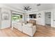 Bright living room with a large comfy white couch, shiplap accent wall, modern ceiling fan, and open access to the pool area at 11828 Ranchers Gap Dr, Odessa, FL 33556