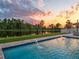 Sparkling swimming pool at sunset with water features and a serene lake view, ideal for relaxation and leisure at 11828 Ranchers Gap Dr, Odessa, FL 33556