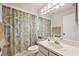 Bright bathroom features a single sink vanity and shower with a leafy patterned shower curtain at 12038 Steppingstone Blvd, Tampa, FL 33635