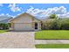 Attractive single-story home showcasing a brick-paved driveway, garage, manicured lawn, and vibrant landscaping at 12038 Steppingstone Blvd, Tampa, FL 33635