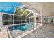 Screened in pool with brick decking and blue sun shade with view of the lush yard at 12038 Steppingstone Blvd, Tampa, FL 33635