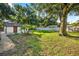 Spacious, partially fenced backyard with mature trees and a shed, creating a private outdoor space at 1217 E 29Th Ave, Tampa, FL 33605