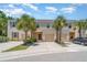 Townhouse exterior featuring a two-car garage, lush palm trees, and neatly landscaped front yard at 12841 Buffalo Run Dr, Gibsonton, FL 33534