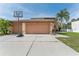 Beautiful exterior of a tan two story home, a three car garage, and basketball hoop at 13003 Carlington Ln, Riverview, FL 33579