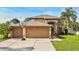 Two-story home featuring a three-car garage, basketball hoop, tropical trees, and a manicured lawn at 13003 Carlington Ln, Riverview, FL 33579