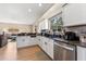 Well-lit kitchen featuring stainless steel appliances, granite countertops, and white cabinets with a view of the living room at 13003 Carlington Ln, Riverview, FL 33579
