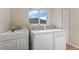 Functional laundry room features a large window, utility sink, and modern washer and dryer set, ideal for convenience at 13003 Carlington Ln, Riverview, FL 33579