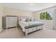 Serene main bedroom featuring a large window, a stylish bed, and a matching dresser at 13003 Carlington Ln, Riverview, FL 33579