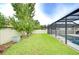 Backyard with a large lawn, privacy fence, and a screened-in pool area, perfect for outdoor relaxation at 13118 Payton St, Odessa, FL 33556