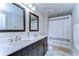 Bathroom featuring double sinks with marble countertops, dark wood cabinets, and a shower with a white curtain at 13118 Payton St, Odessa, FL 33556