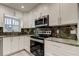 A modern kitchen featuring sleek appliances, white cabinets, and elegant stone countertops at 1402 Provincetown Cir, Lutz, FL 33549